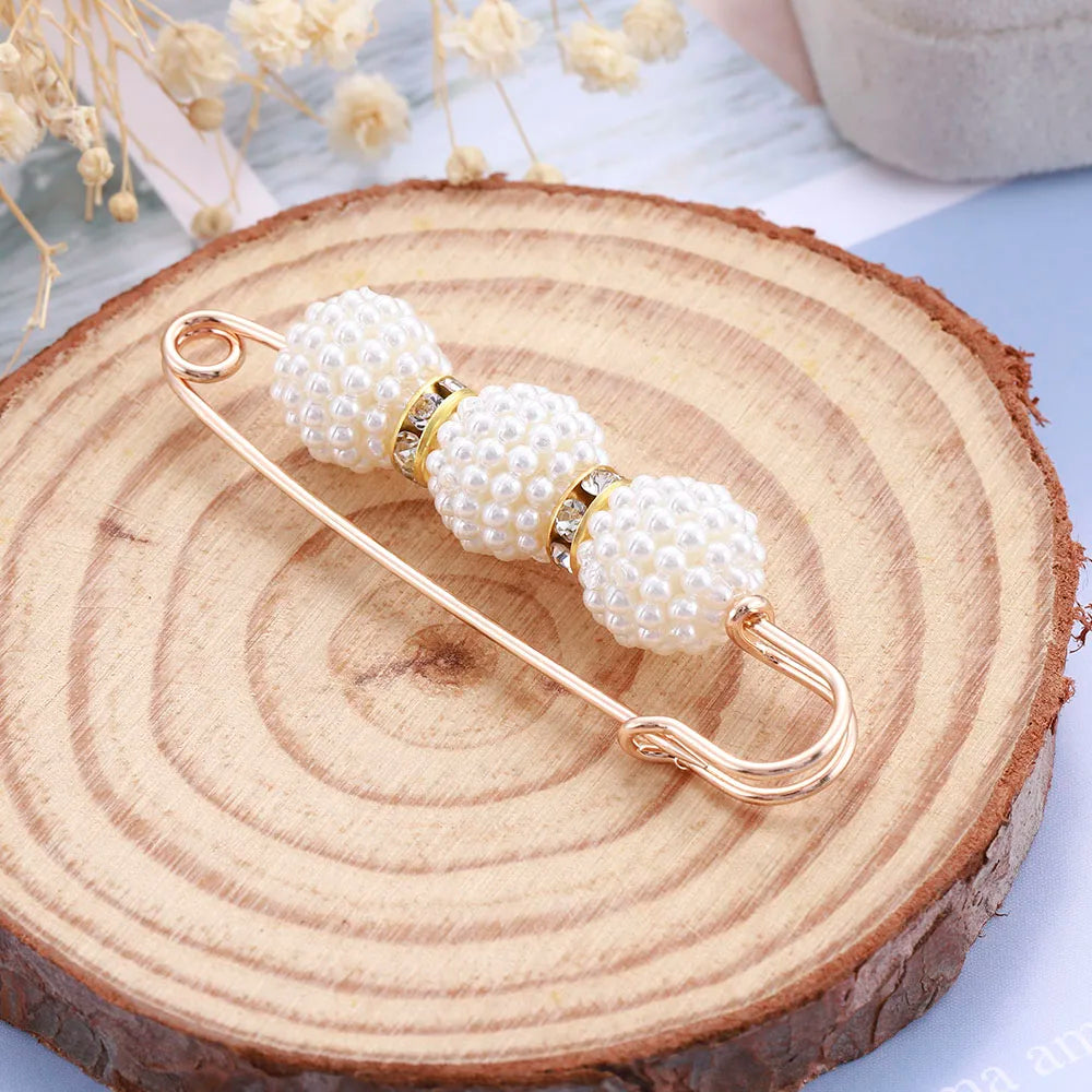 Pearl bow brooch on a wooden surface with dried flowers in the background